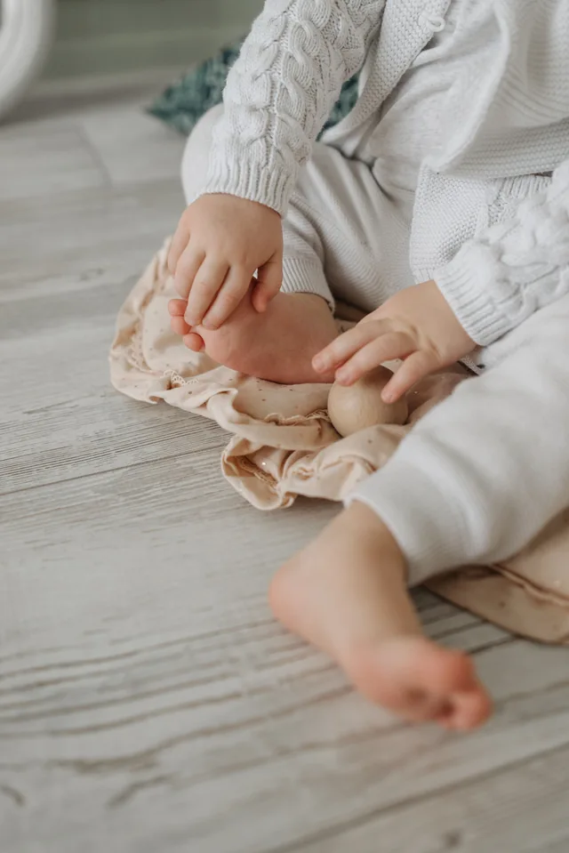 Manos de un niño pequeño sujetando su pie mientras está sentado